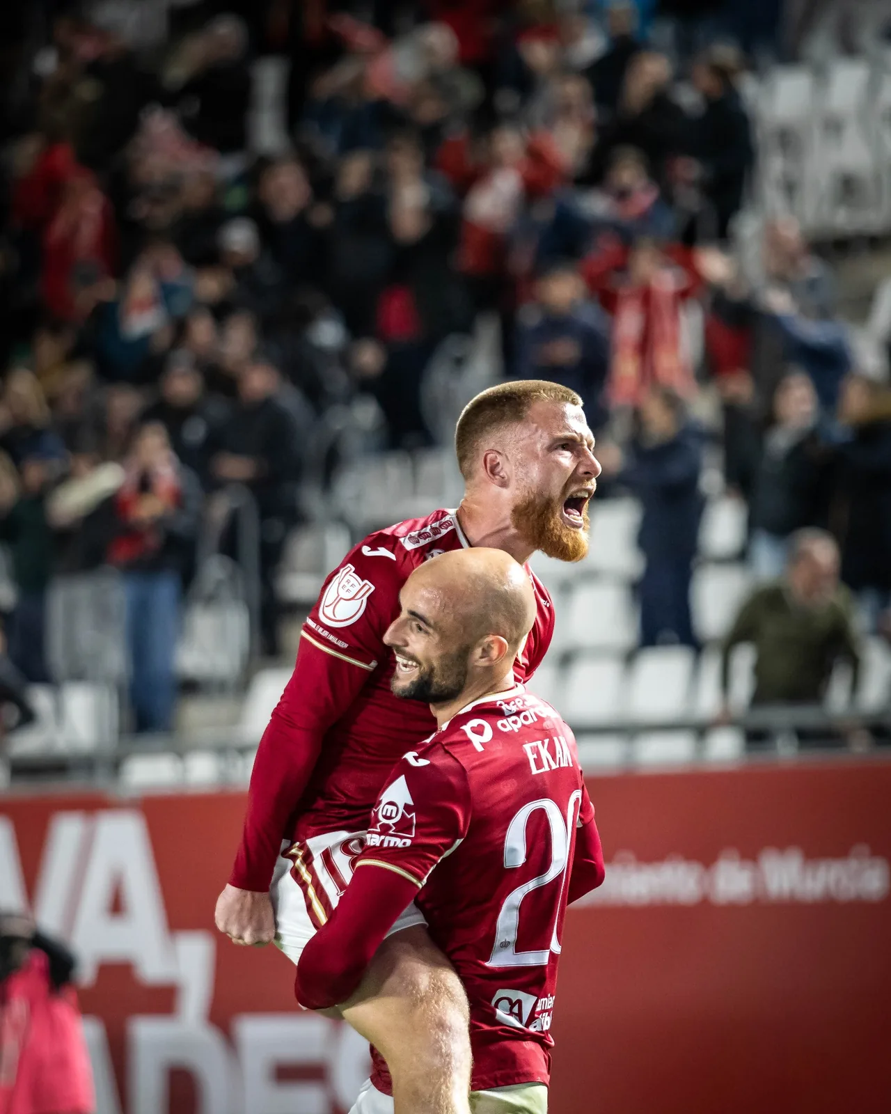 Jugador de fútbol durante una acción de partido con el estadio de fondo